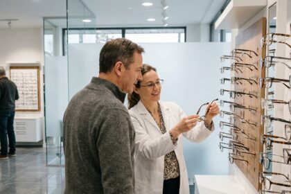 Opticienne conseillant un client sur le choix de montures dans un magasin d'optique moderne et épuré
