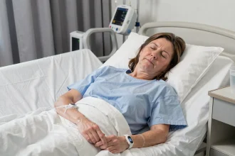 Femme en salle de réveil après une anesthésie générale, connectée à un monitoring médical