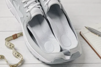 Semelles Akusoli posées dans une chaussure de sport avec accessoires bien-être sur fond blanc
