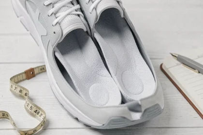 Semelles Akusoli posées dans une chaussure de sport avec accessoires bien-être sur fond blanc